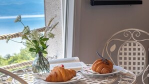 Een tafel met een boek, een vaas met bloemen en twee croissants op borden.