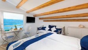 Een slaapkamer met een bed, een televisie, een raam met uitzicht en een kleine tafel met stoelen.