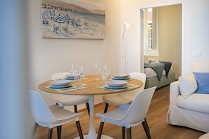 A dining area with a round table, white chairs, and a painting on the wall. - SUMMER HOUSE CAMOGLI - Relax at sunset on the Ligurian coast  (Camogli)