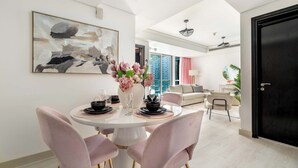 Un comedor moderno con una mesa redonda, sillas rosa y un jarrón de flores.