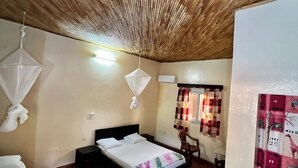 A bedroom with a bed, bedside tables, a chair, a mosquito net, and a curtain with a zebra pattern.