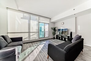 Ein modernes Wohnzimmer mit einem großen Schiebeglasfenster, einem Flachbildfernseher und einer minimalistischen Einrichtung.