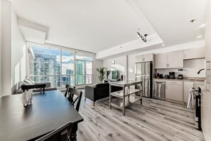 Eine moderne Wohnung mit Essbereich, Küche und großen Fenstern mit Blick auf die Stadt.