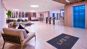 A spacious lobby with a modern design, featuring a reception desk, seating area, and a blue elevator. - Penthouse in Zona T with Rooftop Pool, Sauna & Gym (Bogotá)