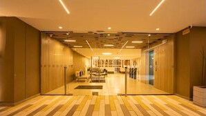 A modern hotel lobby with a central reception desk, a patterned floor, and a ceiling with linear lighting fixtures. - Penthouse in Zona T with Rooftop Pool, Sauna & Gym (Bogotá)