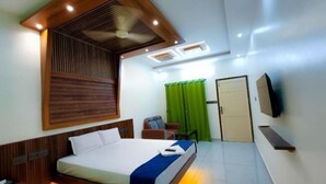 A modern hotel room with a bed, a desk, a chair, a TV, and a green curtain.
