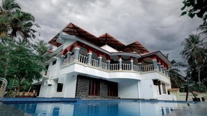 A large, multi-story hotel with a swimming pool in the foreground.