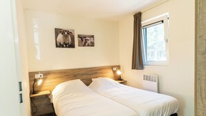 Una camera da letto con una testiera in legno, due comodini con lampade, una finestra con tende e due quadri con immagini di animali appesi al muro.
