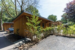 Una cabaña de madera con camino de grava y jardín cercado.