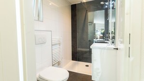 Un bagno moderno con servizi igienici, doccia e mobili bianchi.