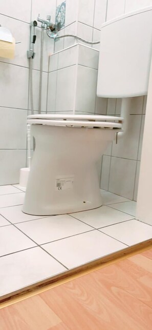 Ein Badezimmer mit Toilette, Dusche und Fliesenboden.
