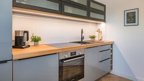 A modern kitchen with a built-in oven, a coffee maker, and a sink. - Villa Alma in Loddin - with balcony and terrace and charging station for e-bikes (Loddin)