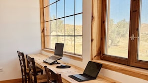 A wooden desk with two laptops and a mouse, positioned near a window with a view of a desert landscape. - Oasis Al Hamam Wellnesscamp  (Lucainena de las Torres)