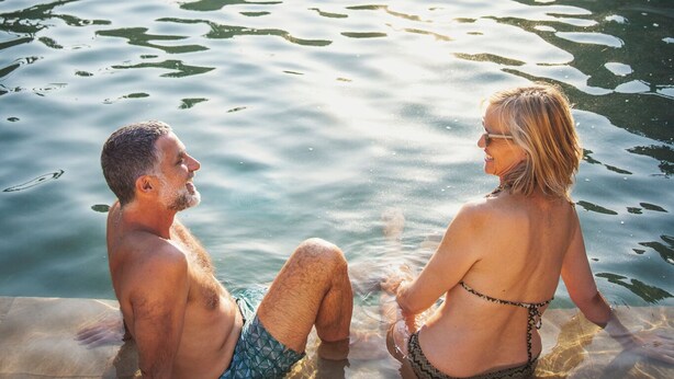 A man and a woman sitting in a stone-walled pool with a fountain. - Oasis Al Hamam Wellnesscamp  (Lucainena de las Torres)