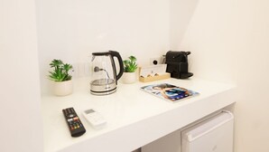 A white countertop with a coffee maker, a remote control, a magazine, and two potted plants. - VivimiHome - MaisonErcolano (Ercolano)