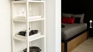 A white shelving unit with kitchenware, a microwave, and wine glasses. - Charming Cosy Studio in Saint-Denis-Stade de France (Saint-Denis)