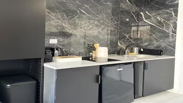 A modern kitchen with a black marble backsplash, a white countertop, and a built-in dishwasher. - Charming Cosy Studio in Saint-Denis-Stade de France (Saint-Denis)