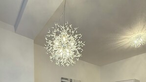 Ein modernes Wohnzimmer mit einem grauen Sofa, einem Betontisch, Holzboden, einem weißen Kleiderschrank und einer Chandeliebre.
