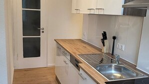 Eine moderne Küche mit weißen Schränken, einer Holz Arbeitsplatte, einem Edelstahl-Spülbecken und einem eingebauten Ofen.