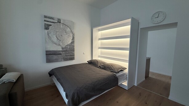 Ein modernes Schlafzimmer mit einem Bett, einer Wanduhr und einem einzigartigen, runden Kunstwerk.