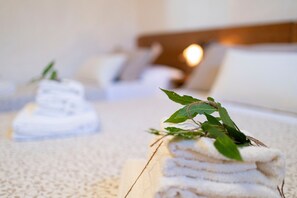 Un conjunto ordenado de toallas con una planta encima, sobre el suelo alfombrado en una habitación de hotel.
