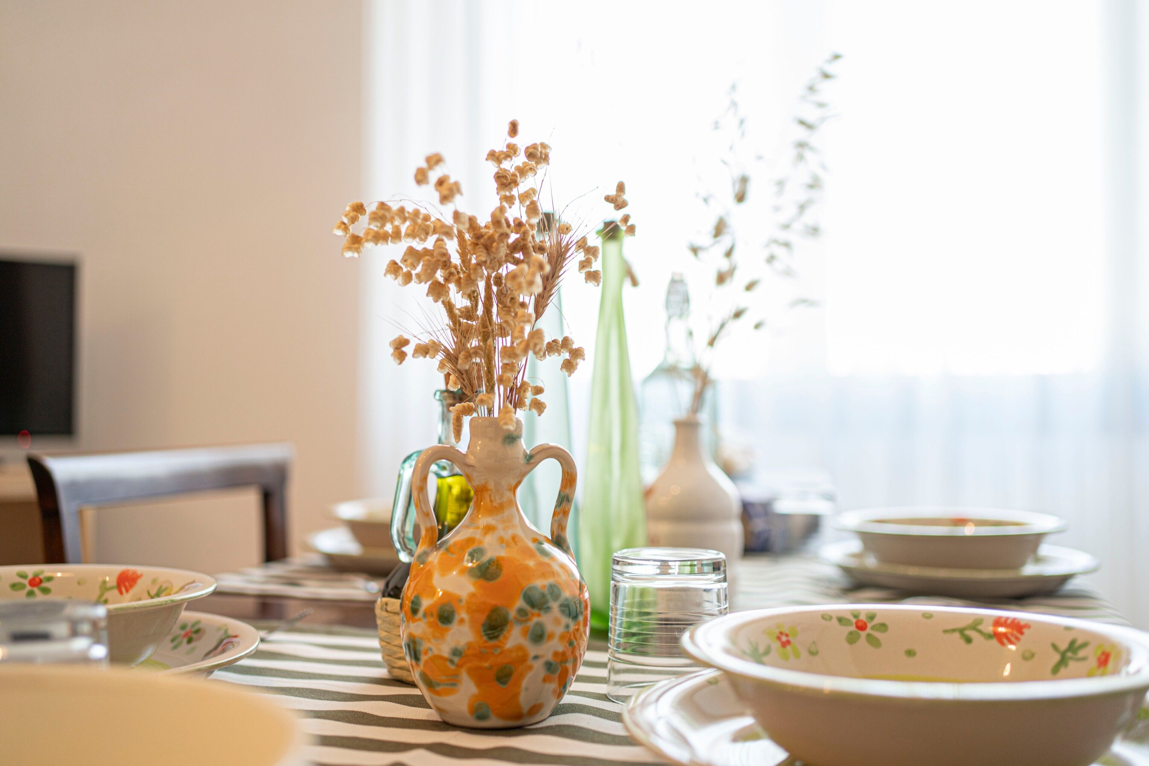 Une table à manger avec une carafe, des bols et un verre.