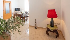 Un couloir comprenant un coin repas, un téléviseur, une lampe et une plante en pot.