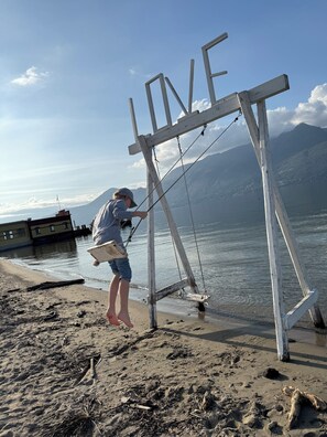 A person standing on a sandy beach, using a white metal structure with ropes to reach into the water. - 75-square-meter apartment, first floor, terrace, 2 bedrooms, bathroom with shower, and separate toilet. Restroom, max. 5 people (Agra)