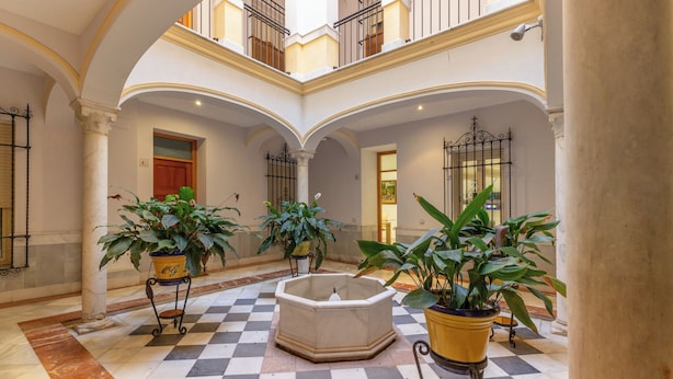 A spacious atrium with a checkered floor, multiple potted plants, and a central fountain. - Fuente de plata, Historical Center, Step-free access (Sevilla)