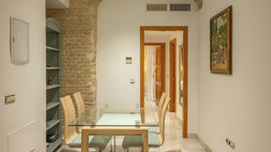 A dining area with a glass table and chairs, a brick wall, and a painting on the wall. - Fuente de plata, Historical Center, Step-free access (Sevilla)