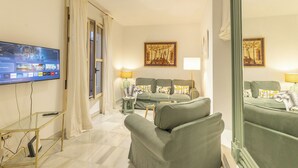 A modern living room with a flat-screen TV, green sofas, a coffee table, and artwork on the walls. - Fuente de plata, Historical Center, Step-free access (Sevilla)