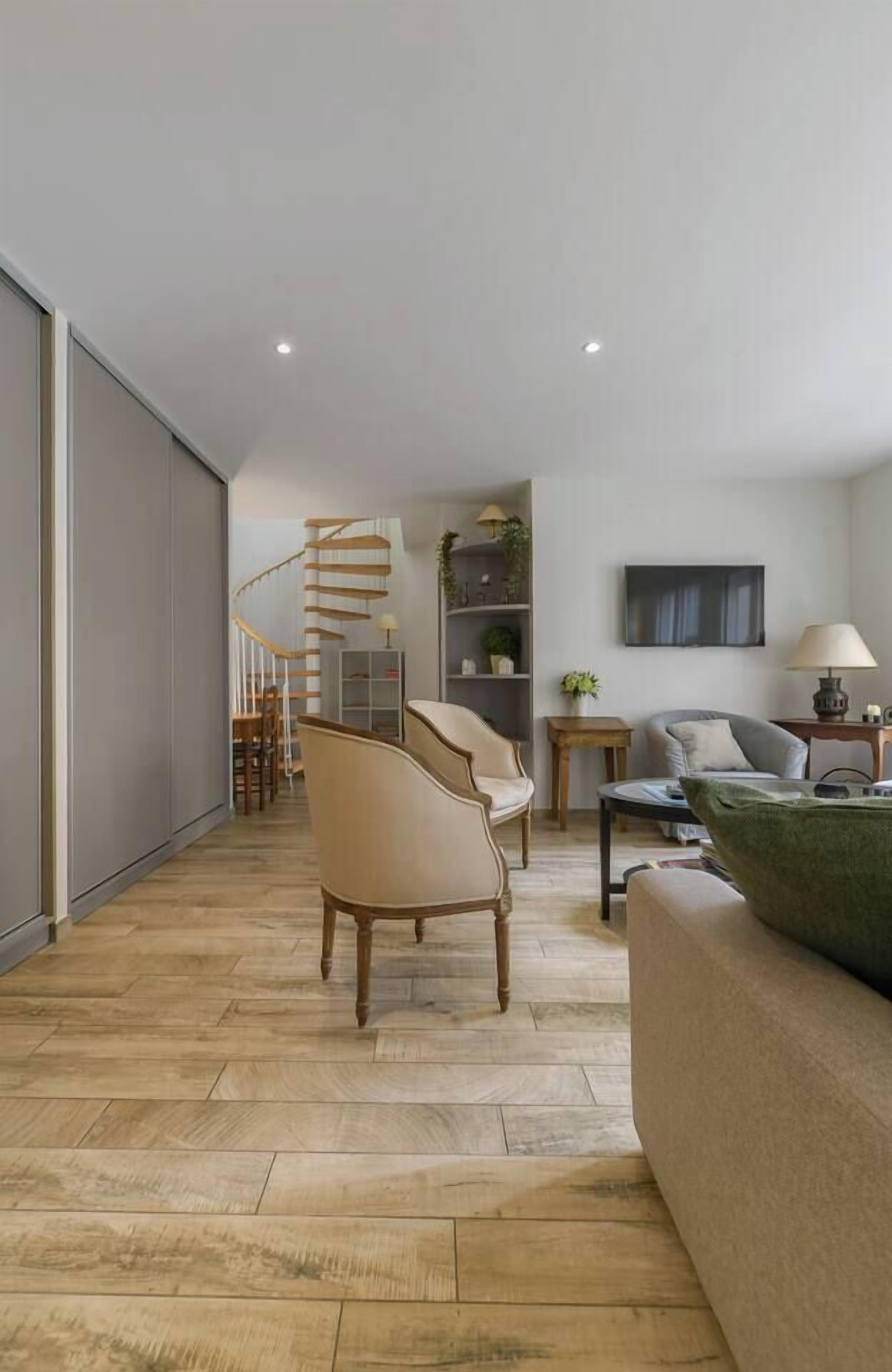 Ein modernes Wohnzimmer mit Wendeltreppe, Holzboden und einer Couch.