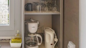 A kitchen with a built-in cabinet containing various kitchenware and appliances. - Appartement Cosy en centre ville avec parking (Clermont-Ferrand)