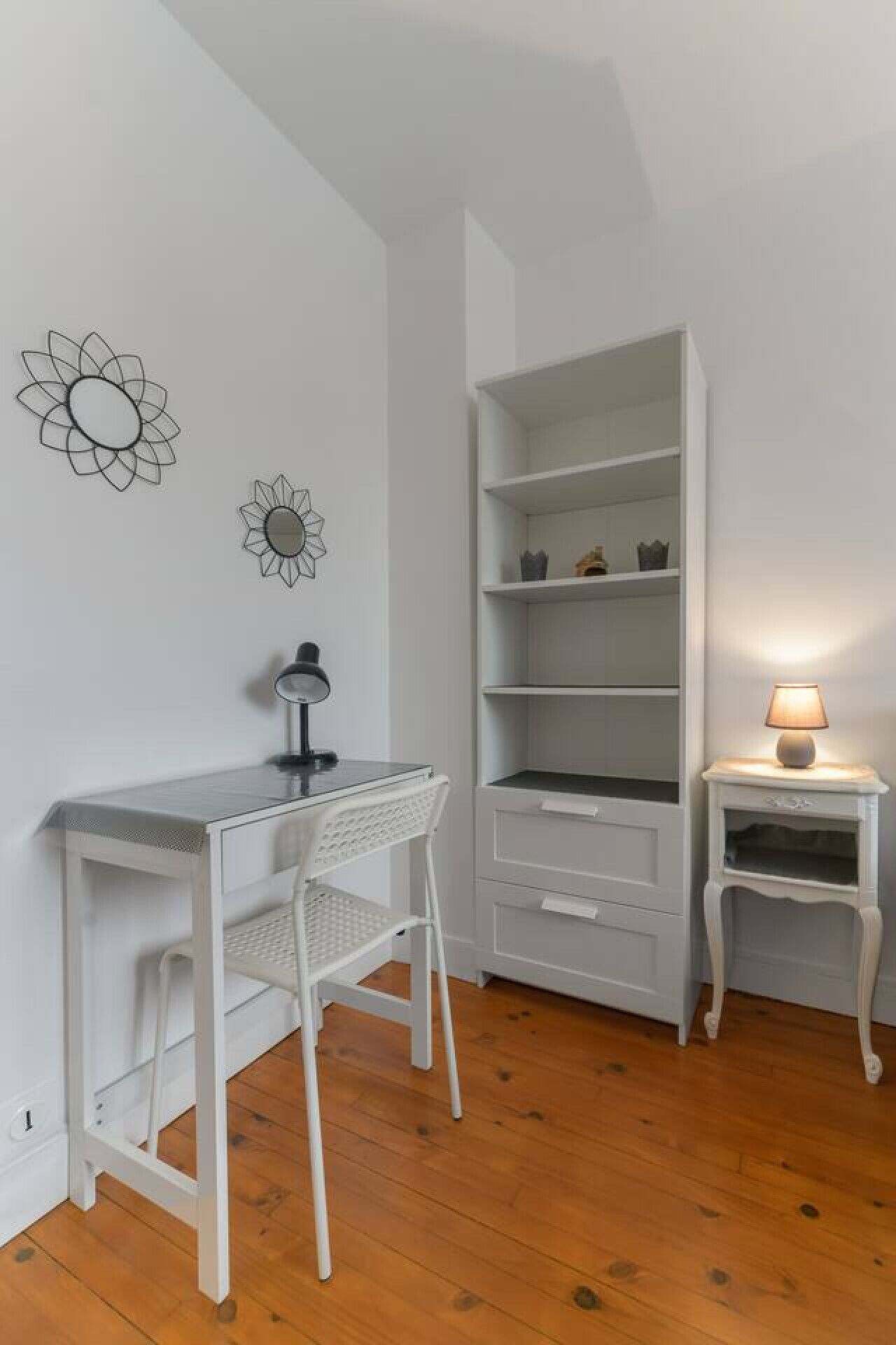 Una habitación con un escritorio blanco, una silla y estanterías abiertas.