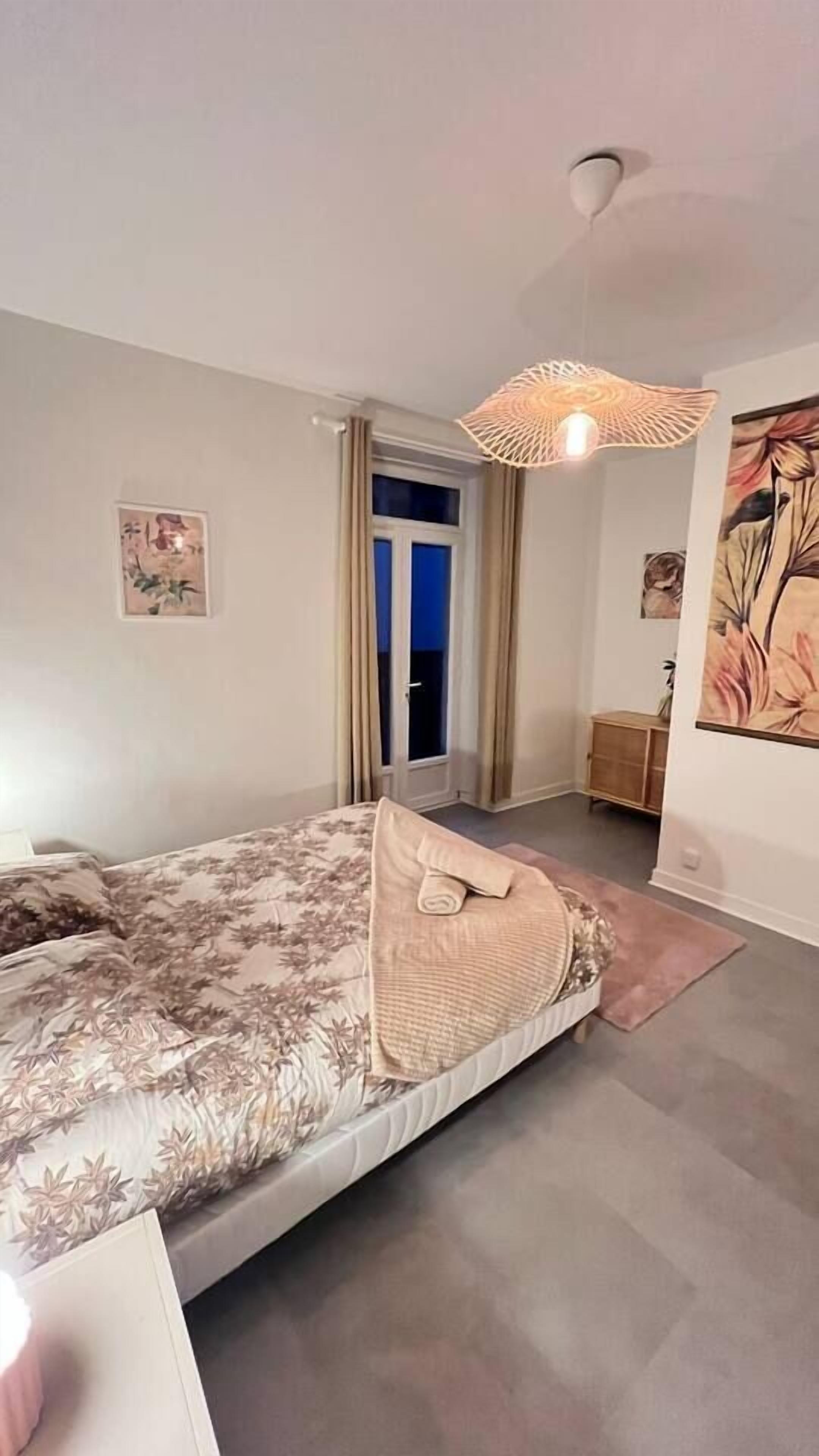 Una camera da letto con un letto, una porta che dà su un balcone e una lampada a soffitto.
