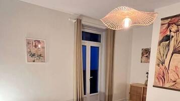 Una camera da letto con un letto, una porta che dà su un balcone e una lampada a soffitto.