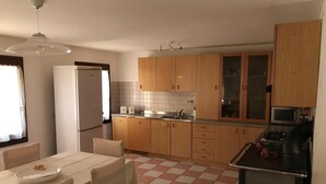 Une cuisine compacte dotée de meubles en bois, d’un réfrigérateur, d’un four à micro-ondes et d’un coin repas avec une table et des chaises.
