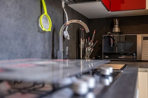 Eine Küche mit Mikrowelle, Kaffeemaschine und Besteck auf der Arbeitsfläche.