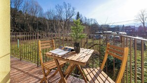 A wooden table and chairs on a balcony with a view of trees and houses. - Colorful Apartment in Wisla | 2 Bedrooms | Workspace. (Wisła)