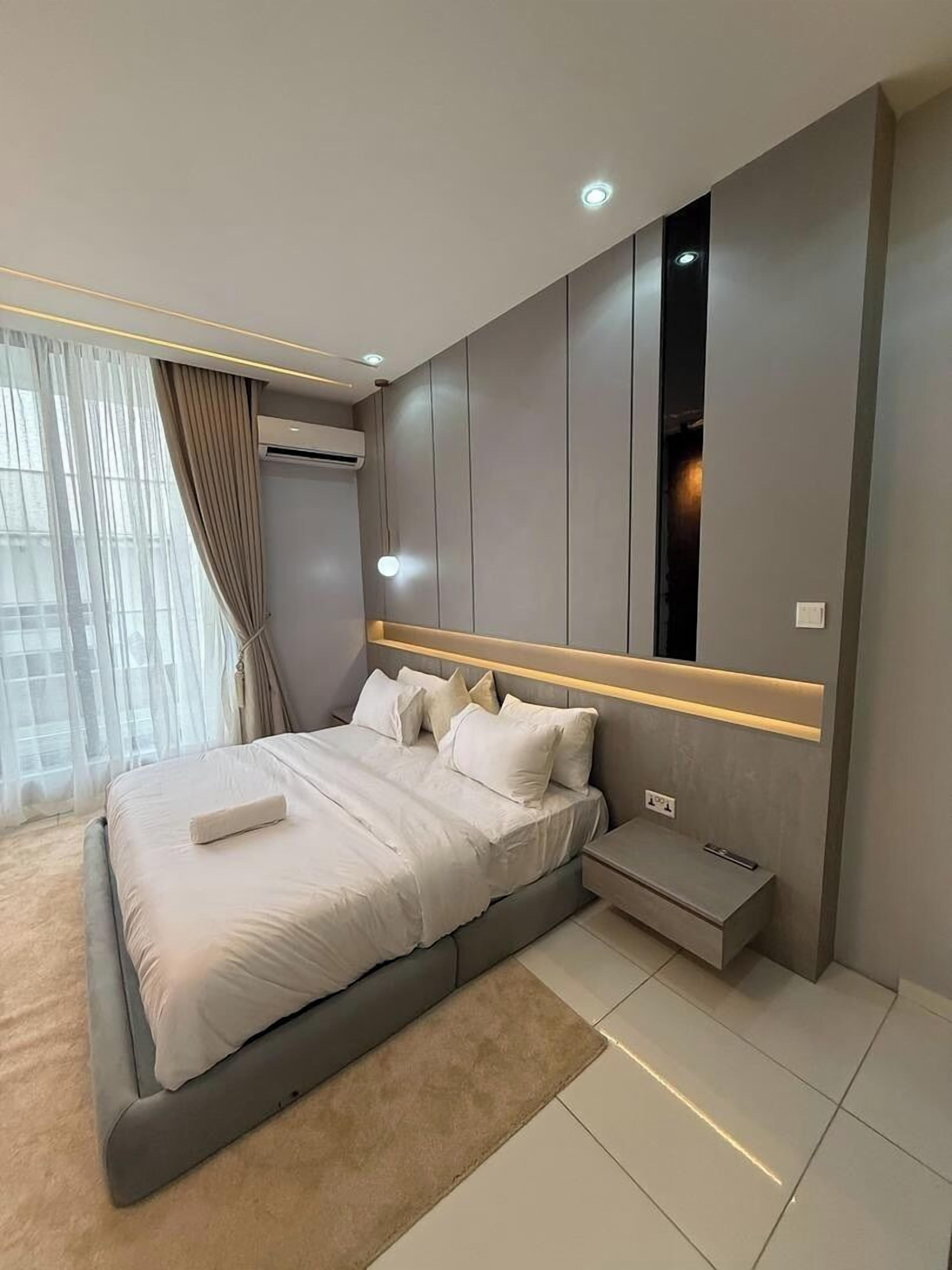 Une chambre moderne avec un grand lit, une table de chevet et un téléviseur intégré.