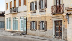 Un edificio con varias ventanas, una puerta con celosía decorativa y un pequeño balcón con barandilla de hierro forjado.