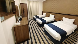 A hotel room with two beds, a wooden headboard, a flat-screen TV, a desk, and a coat rack. - Asfour Hotel 01 (Makkah)