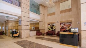 A spacious lobby with a reception desk, seating area, and a coffee corner. - Asfour Hotel 01 (Makkah)