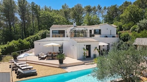 Ein zweistöckiges Haus mit Schwimmbad, Sitzgelegenheit im Freien und einem Garten.