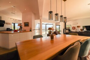 A modern kitchen with a wooden island, pendant lights, and a dining area with a large table and chairs. - Magnificent Villa – La Villa Blanc (Tourrettes)