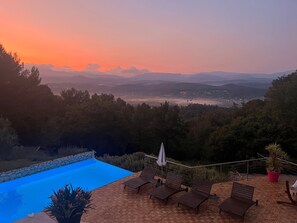 A pool with lounge chairs, a stone wall, and a view of distant mountains. - Magnificent Villa – La Villa Blanc (Tourrettes)