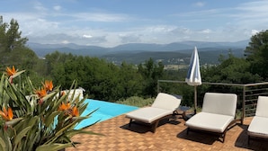 Ein Poolbereich mit Liegestühlen und Blick auf Berge.