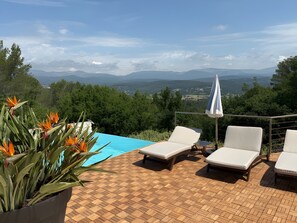 Ein Poolbereich mit Liegestühlen und Blick auf Berge.