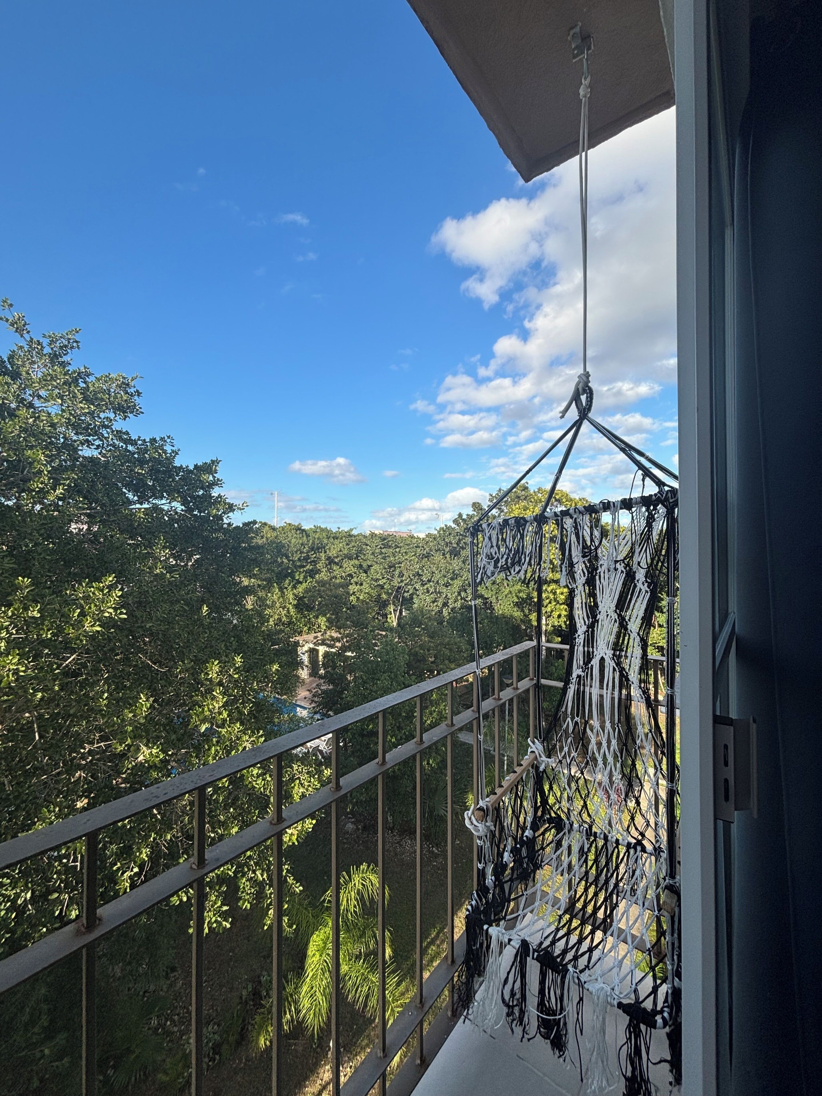 Un balcon offrant une vue sur un paysage verdoyant et luxuriant et sur un ciel bleu azur.