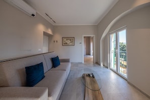 Un saló modern amb un sofà, una taula de centre de vidre i una finestra gran.